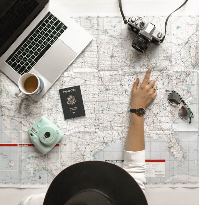 hero-img-01 Hand on map with camera, passport, laptop, and coffee, perfect for travel planning inspiration.