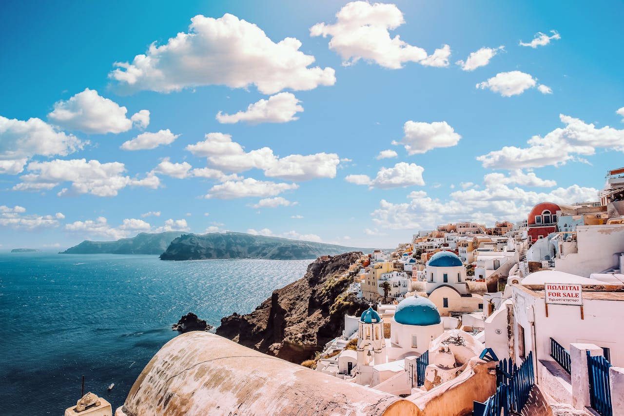 hero-img-02 Captivating view of Santorini's famous blue-domed buildings under a vibrant sky.